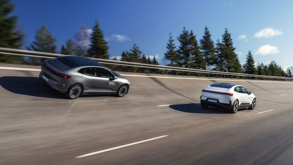 Two Polestar 4 cars driving on an asphalt road, surrounded by forest