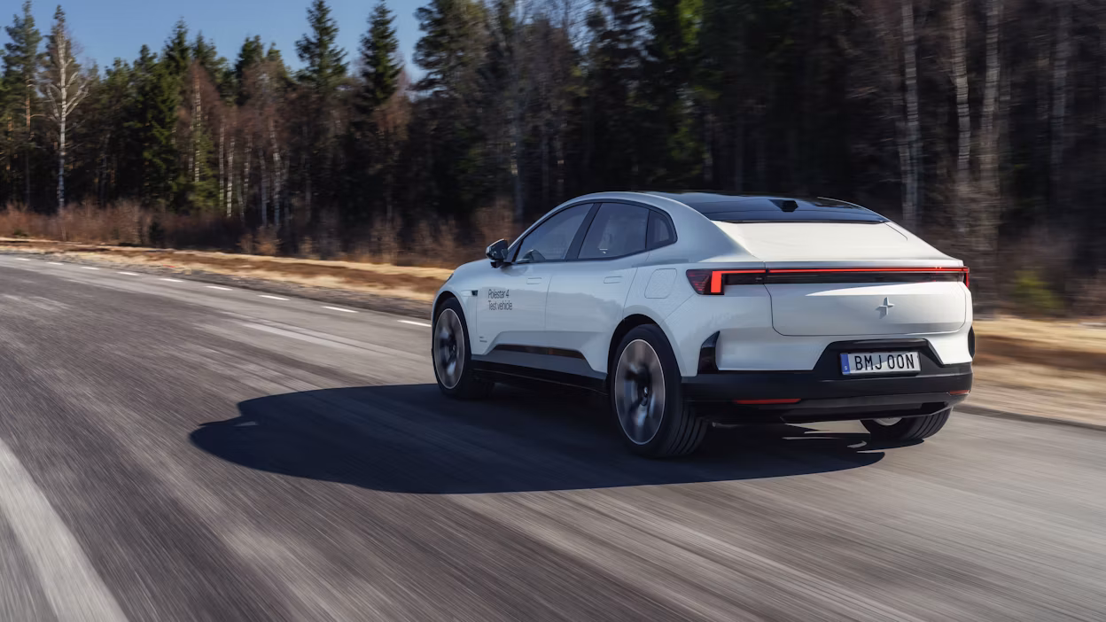 Polestar 4 in Snow color driving on an asphalt road, viewed from the rear