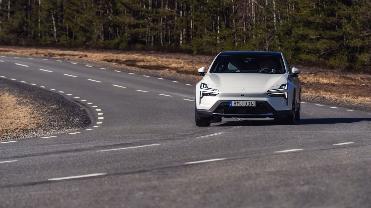 Polestar 4 in Snow color driving on an asphalt road, viewed from the front