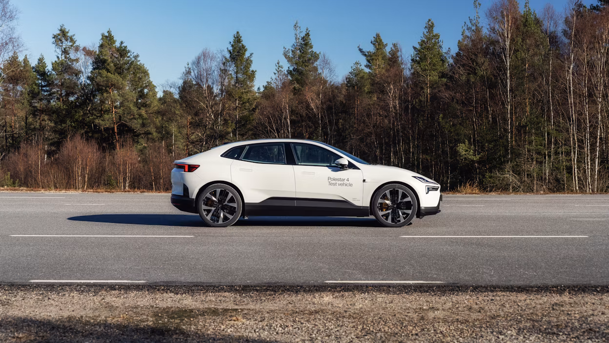 Polestar 4 in Snow color driving on an asphalt road, viewed from the side
