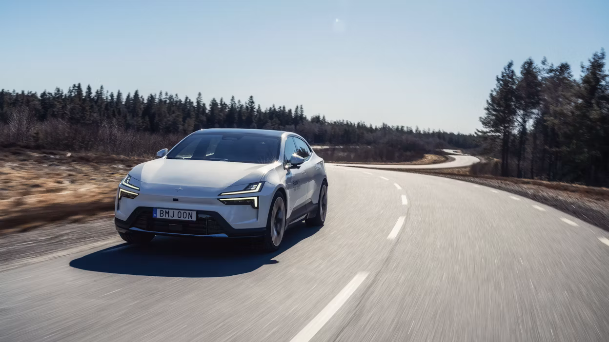 Polestar 4 in Snow color driving on a road surrounded by forest