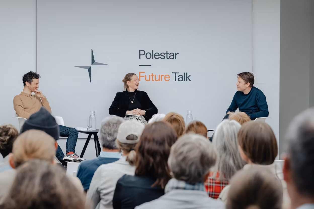 Panel discussion with three speakers seated on stage, audience in foreground, Polestar Future Talk branding on wall.