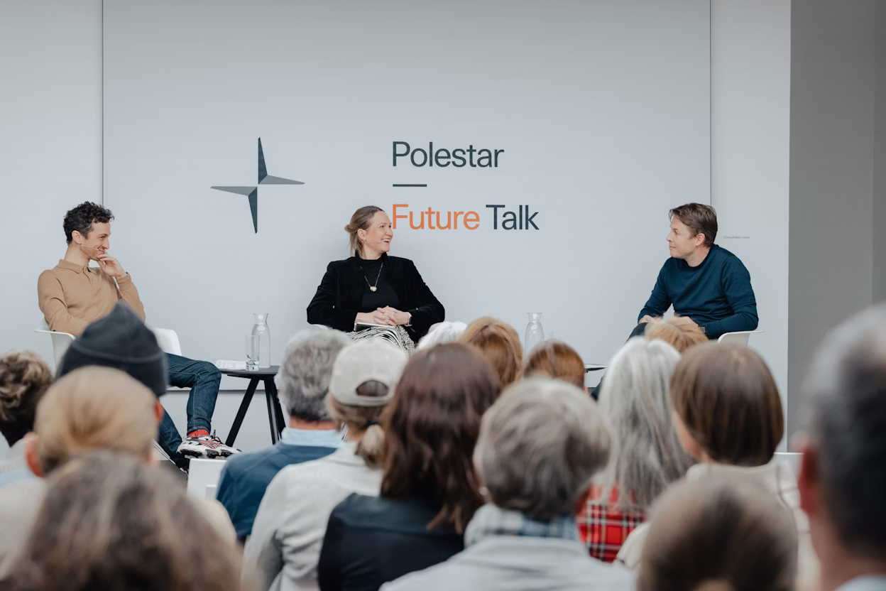 Panel discussion with three speakers seated on stage, audience in foreground, Polestar Future Talk branding on wall.