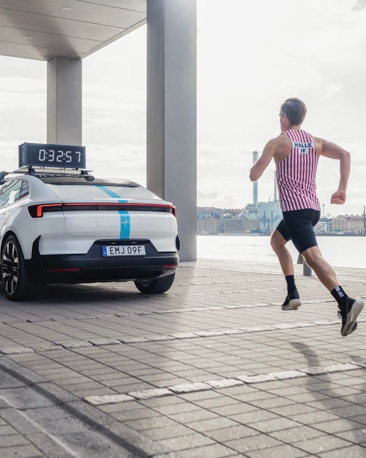 Runner behind a blue striped Polestar 4 with a timer on the car roof