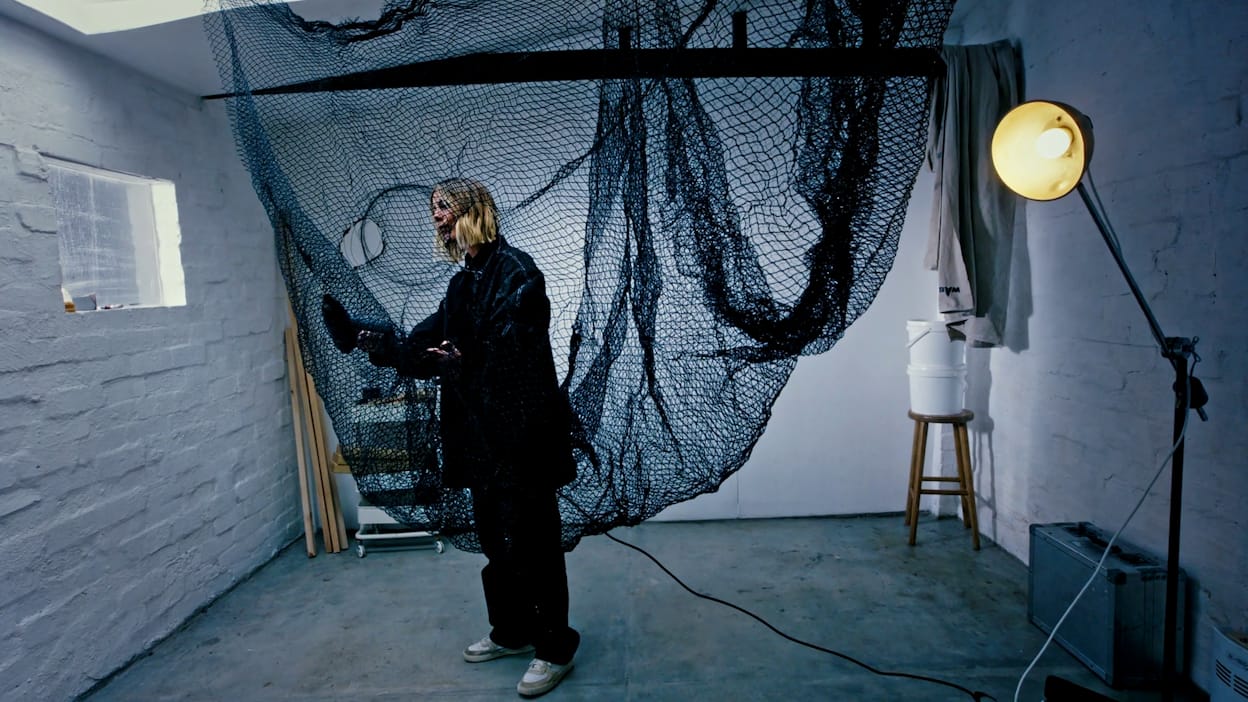 Artist Emily Medbury works on art in her studio. The artwork is made from recycled fishing net