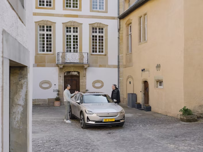 Two people standing near a Polestar car in a courtyard surrounded by historic buildings.