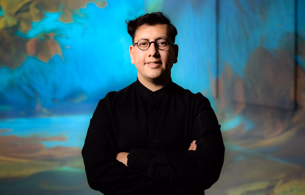 Profile image of digital artist Refik Anadol standing in front of artwork