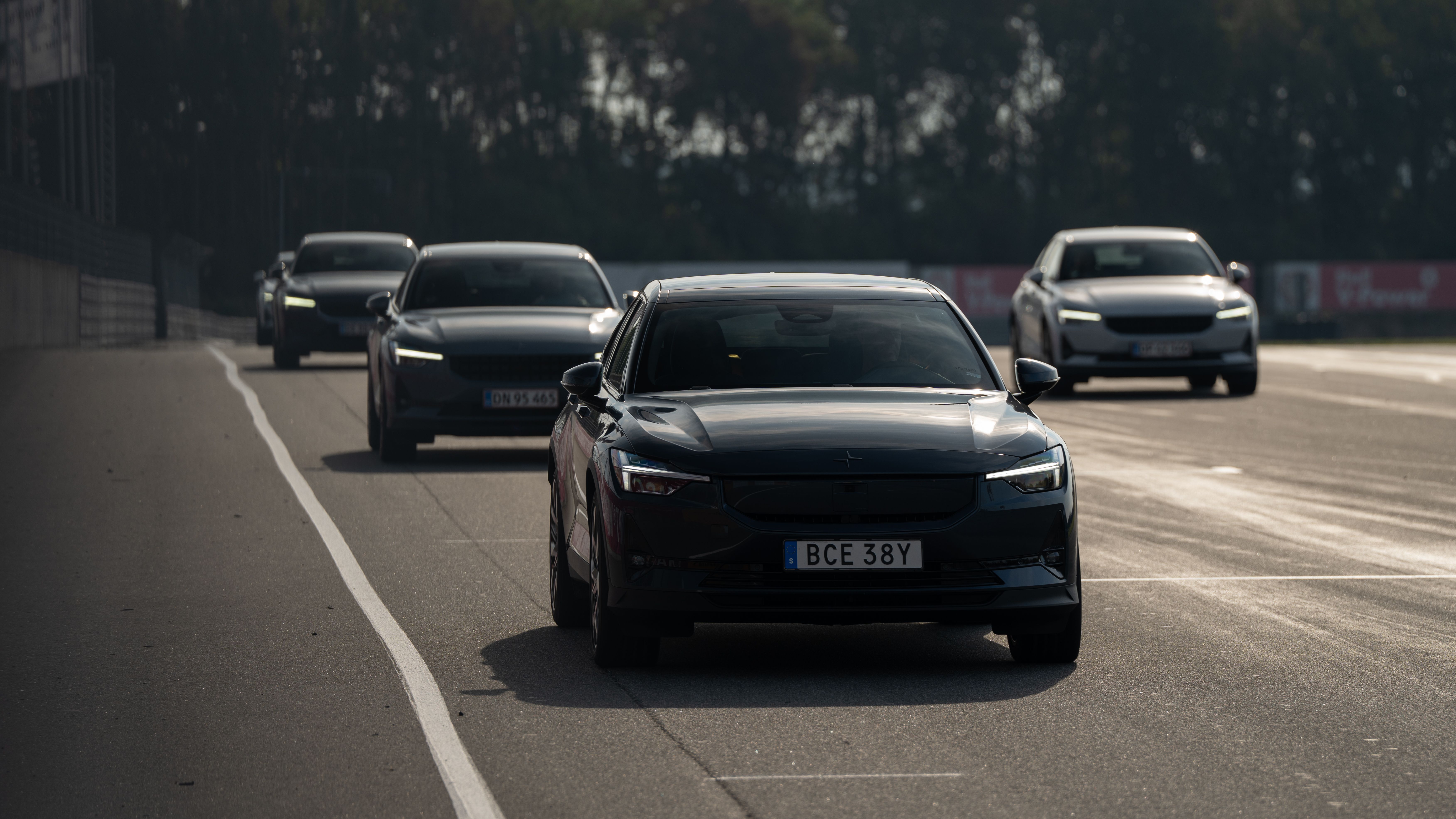 Polestar cars driving on a road with trees in the background.