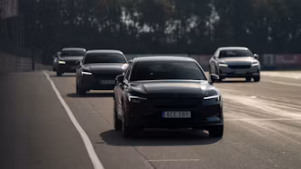Polestar cars driving on a road with trees in the background.
