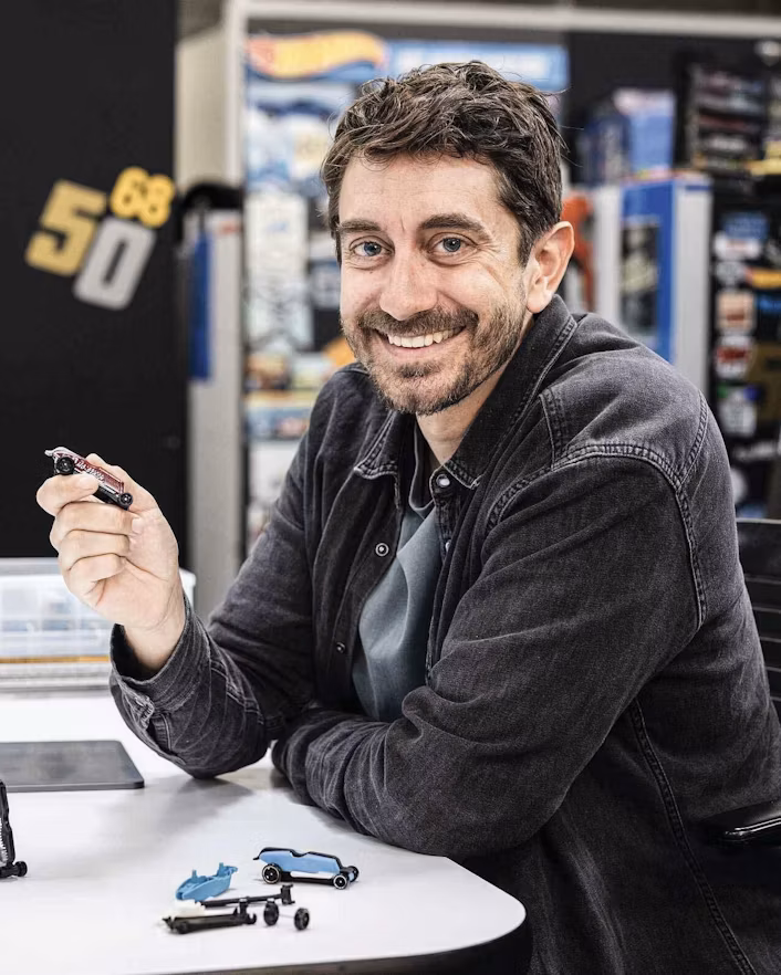 Man sitting at desk holding toy car
