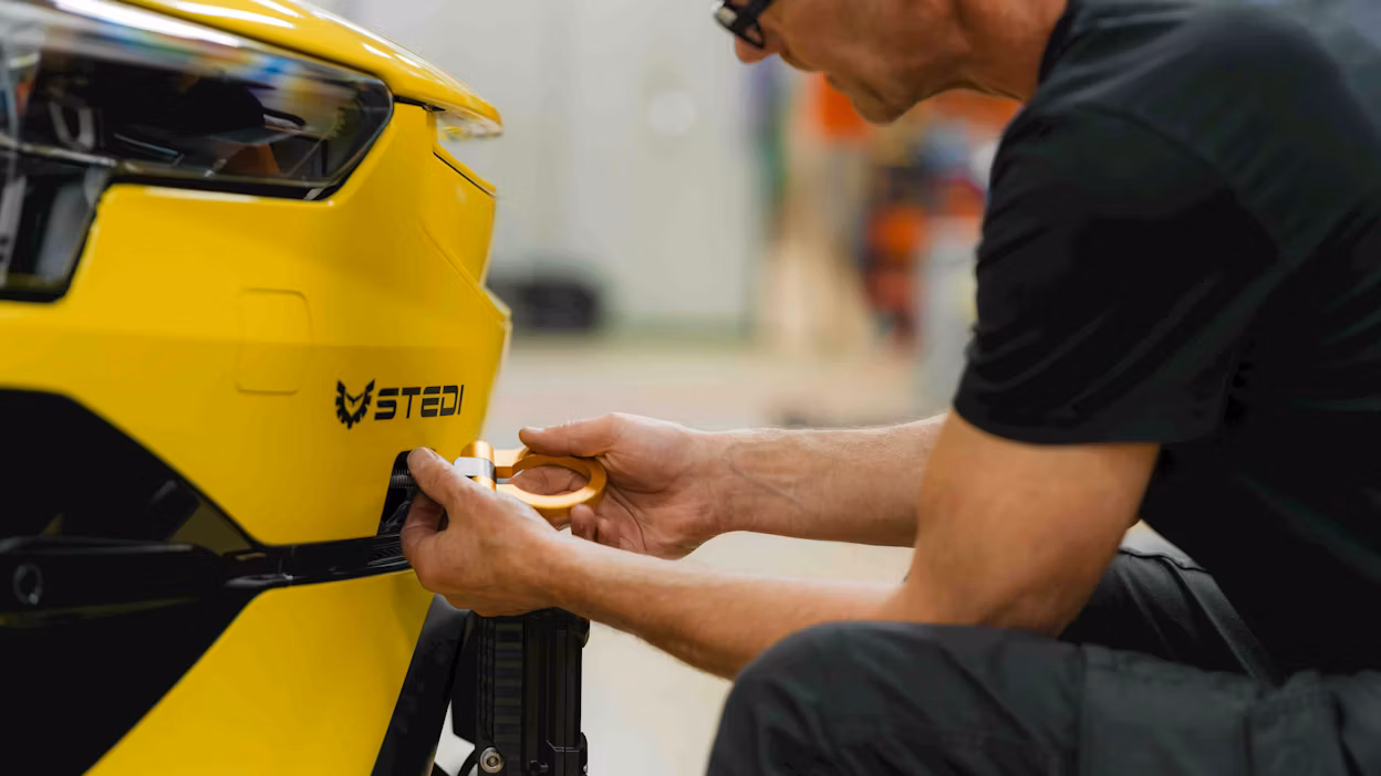 An engineer attaching a tow hook to the front of a car