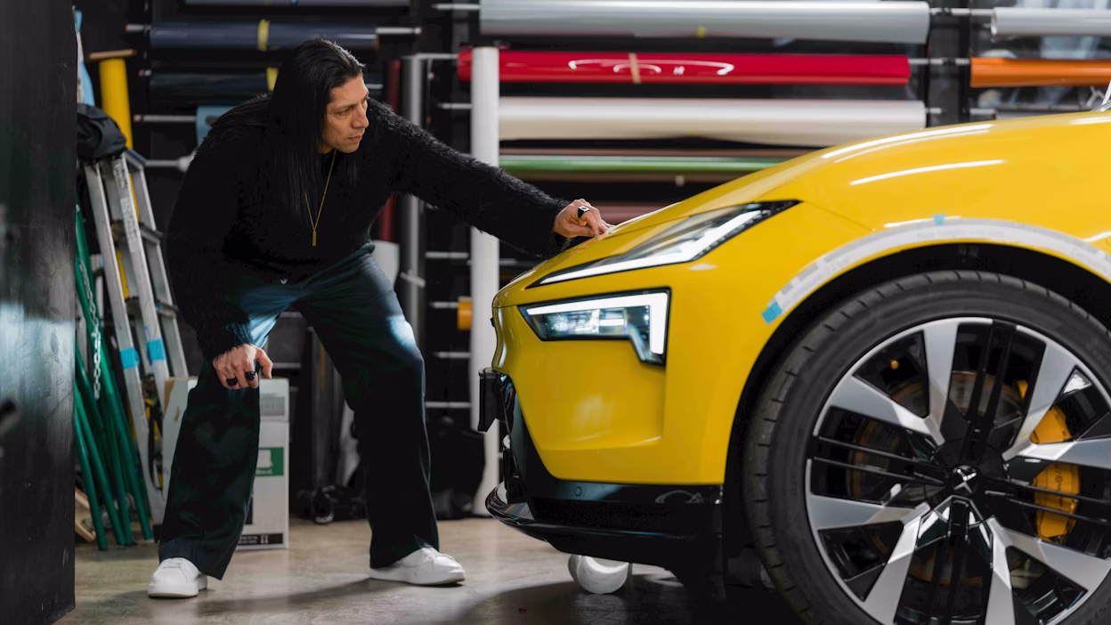 A designer inspecting the front of a yellow car