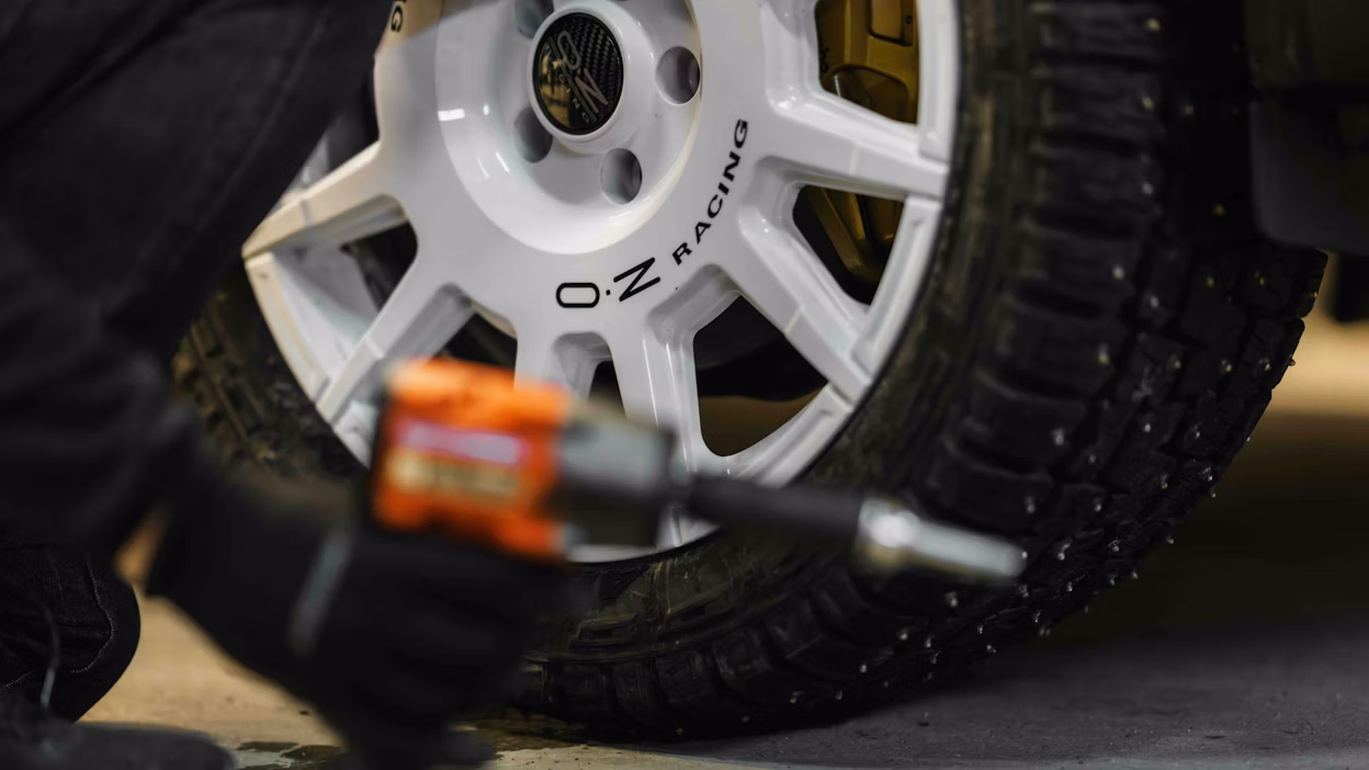 A mechanic kneeling in front of white racing wheels