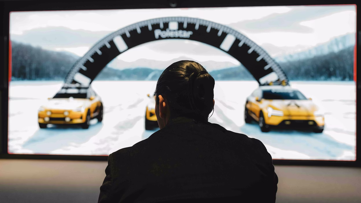A designer looking at renderings of new cars on a large screen