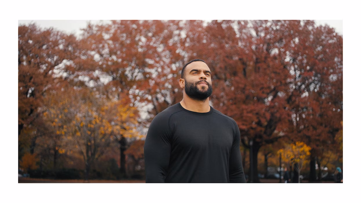 Solomon Thomas staat in een park met bomen op de achtergrond.