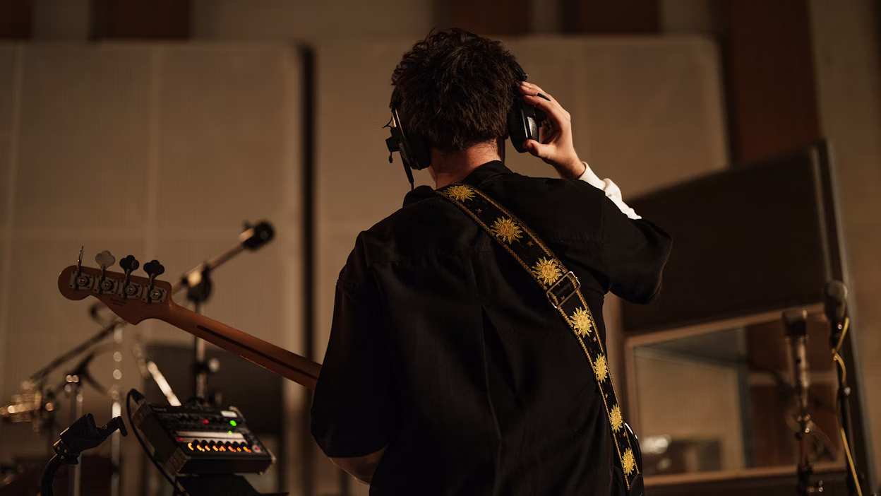 Back on man in recording studio playing guitar