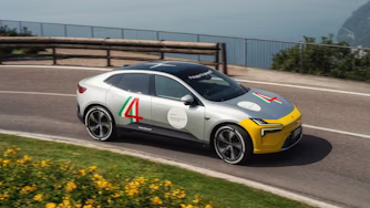 Polestar 4 i racingdekaler kör på asfalterad väg med hav i bakgrunden