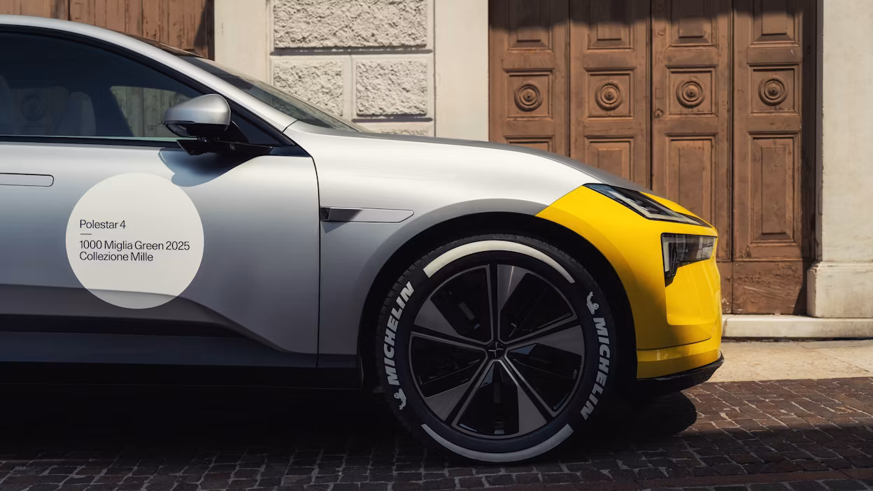 Polestar 4 i racingdekaler står på en stenbelagd väg med en grå stenbyggnad med trädörr som bakgrund