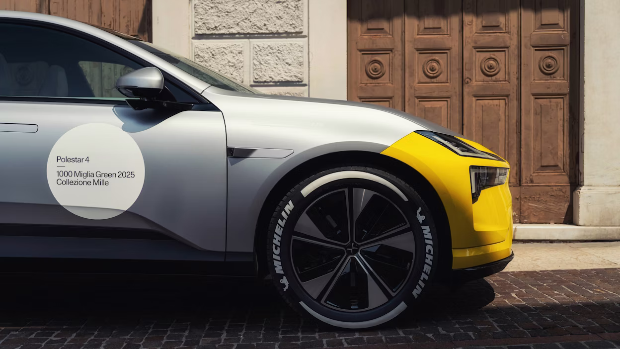 Polestar 4 i racingdekaler står på en stenbelagd väg med en grå stenbyggnad med trädörr som bakgrund