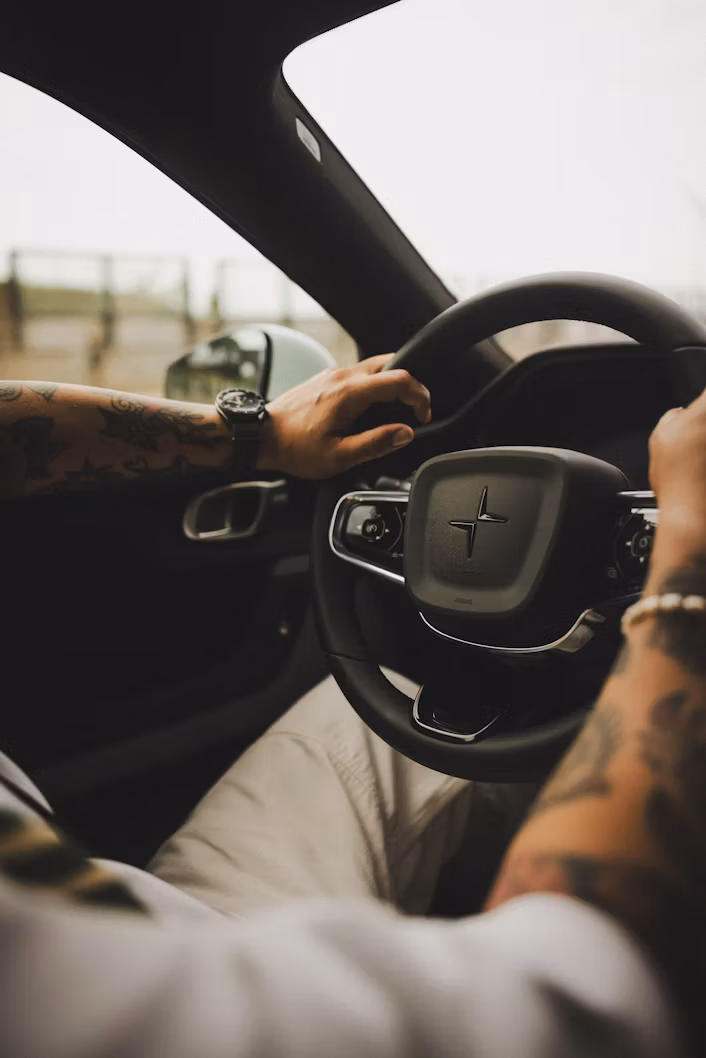 Close-up van een bestuurder met handen op het stuur.