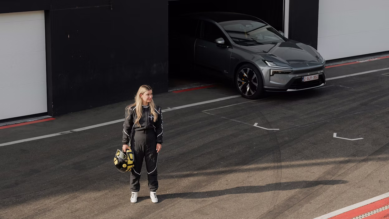 Woman in racing outfit standing in front of Polestar 4