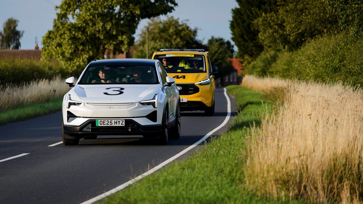 Vit Polestar 3 kör med följebil på asfalterad väg med träd i bakgrunden