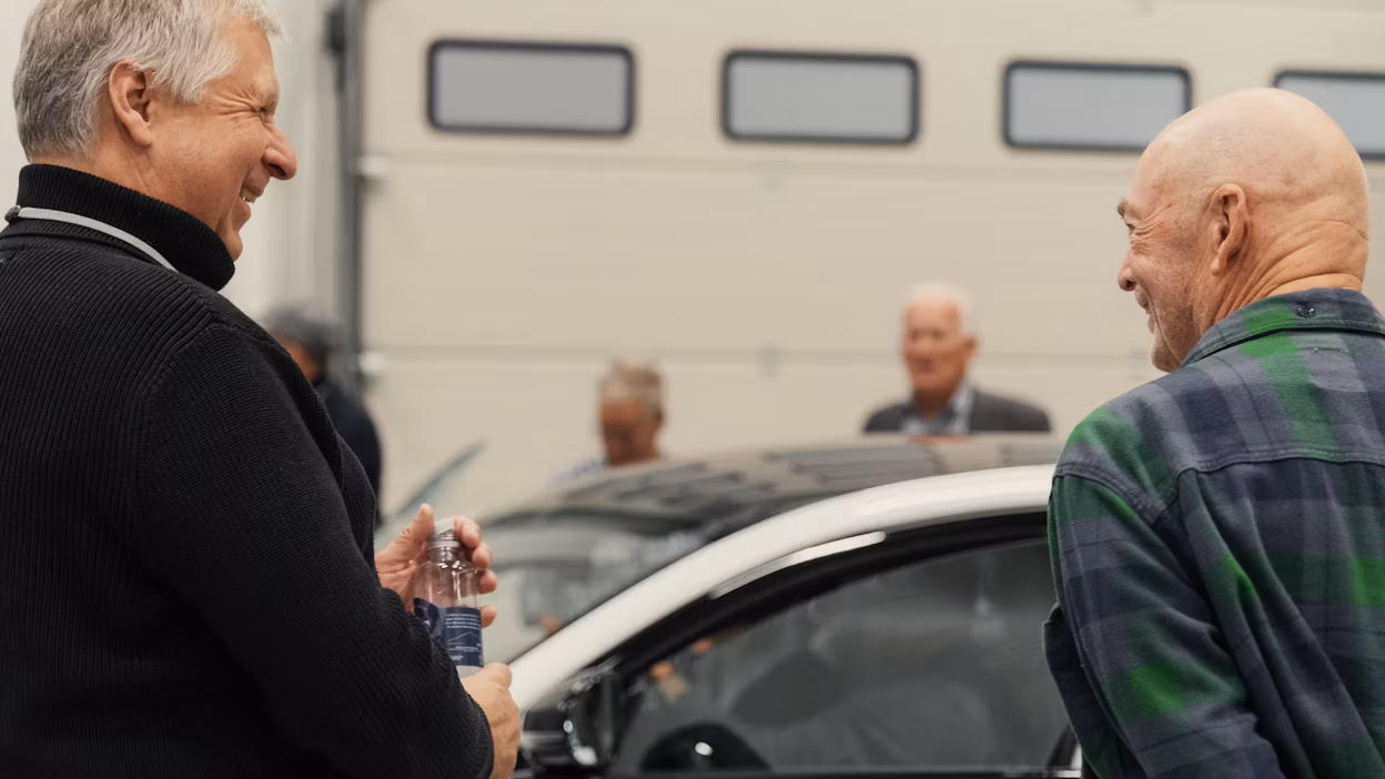 two people smiling and a car in the background