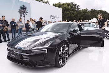 Polestar 5 staat op een wit platform met mensen eromheen.