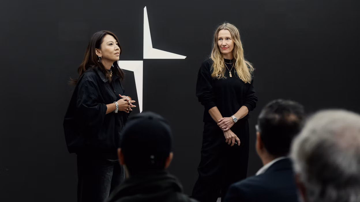 Two pesenters talking in front of a crowd, black backdrop with the Polestar logo
