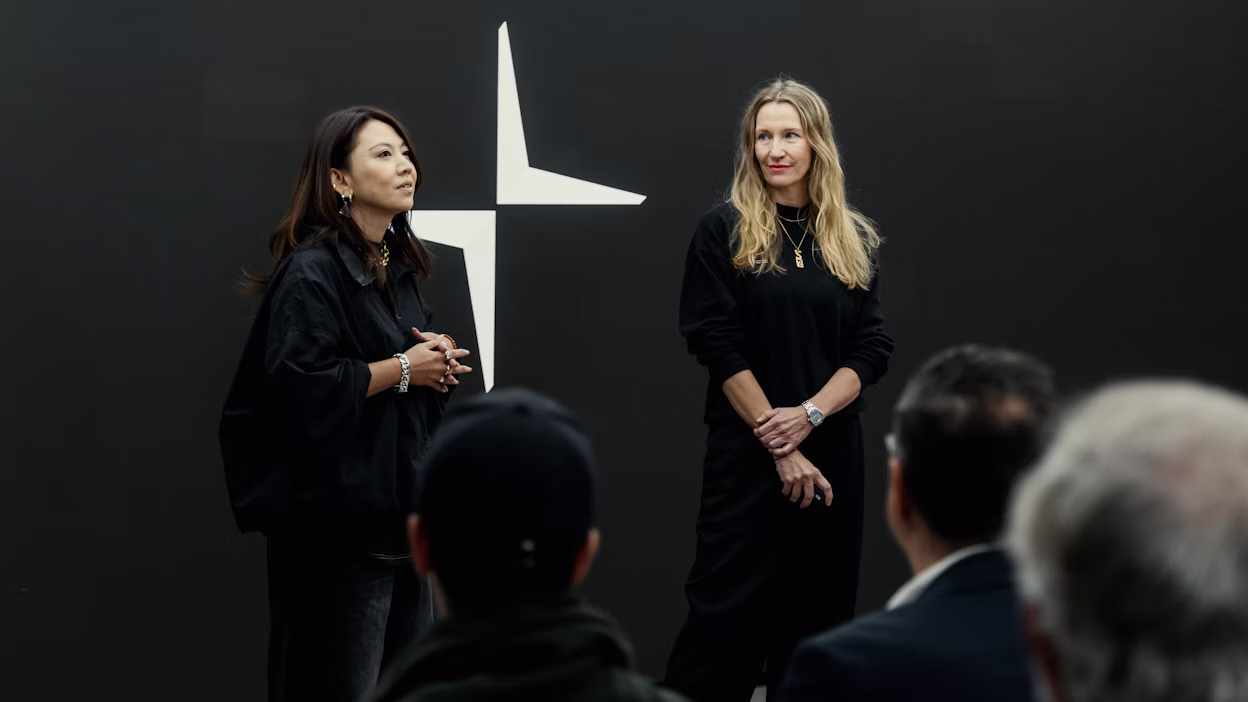 Two pesenters talking in front of a crowd, black backdrop with the Polestar logo