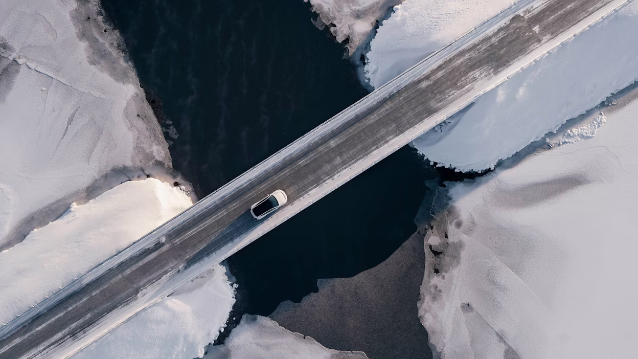 White Polestar driving on a bringe between ice blocks