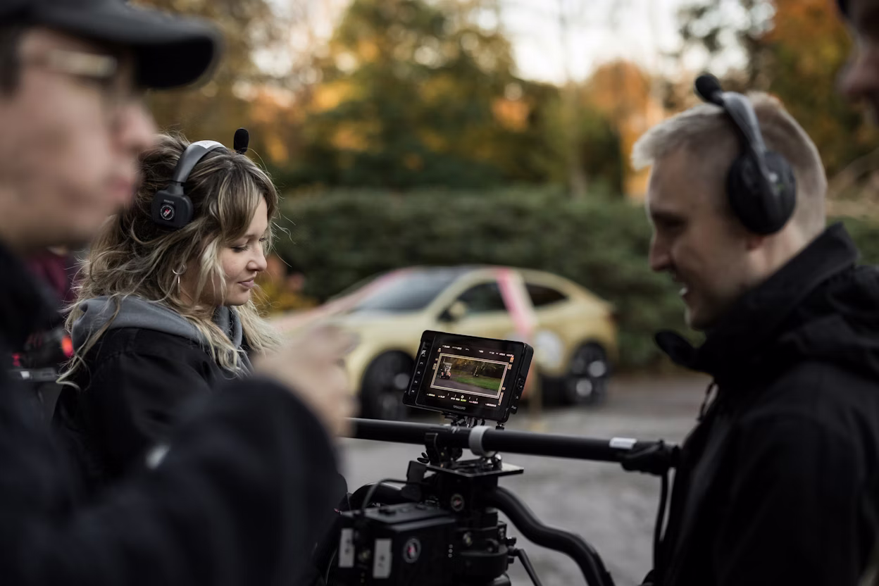 Camera workers on set for movie recording, golden Polestar 4 in the background and the camera and team in the foreground