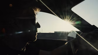 Face of man driving Polestar with sun shining through window