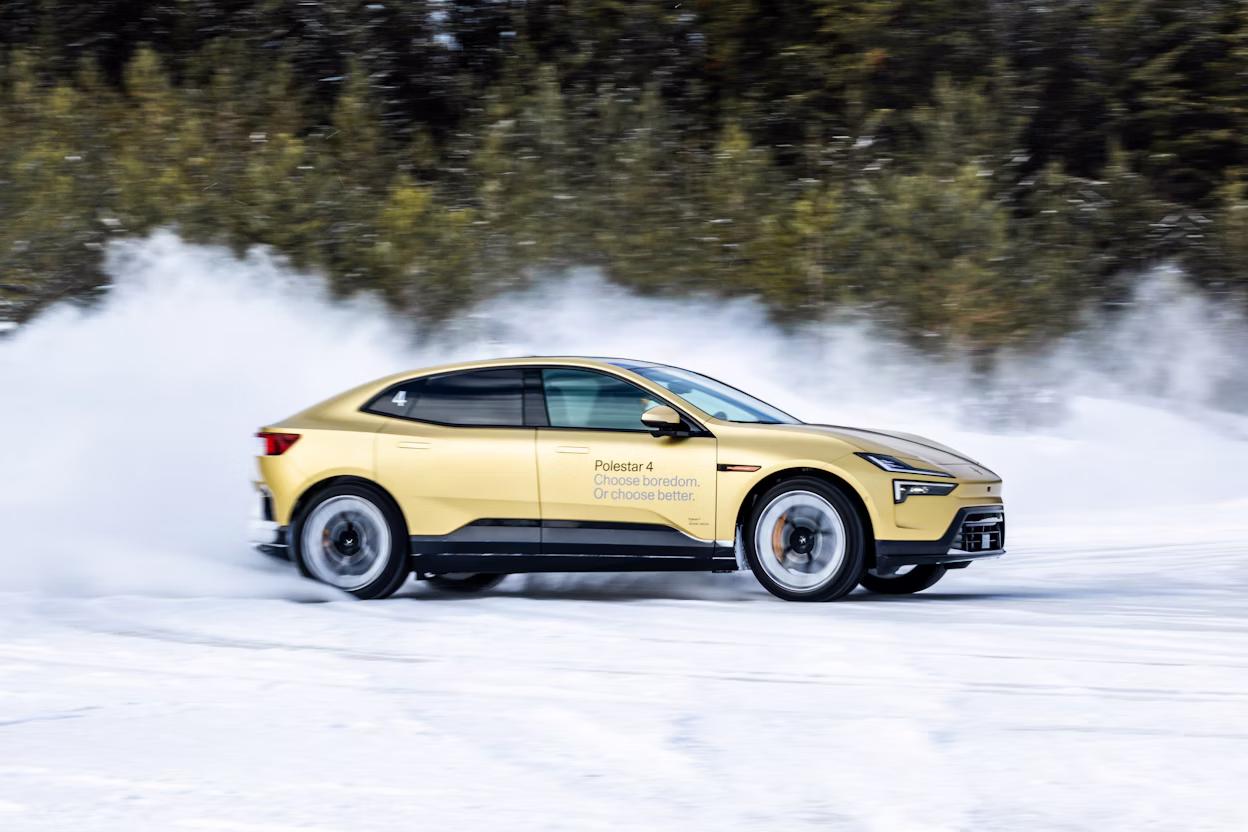 Polestar 4 driving on snow with snow spray, trees in background