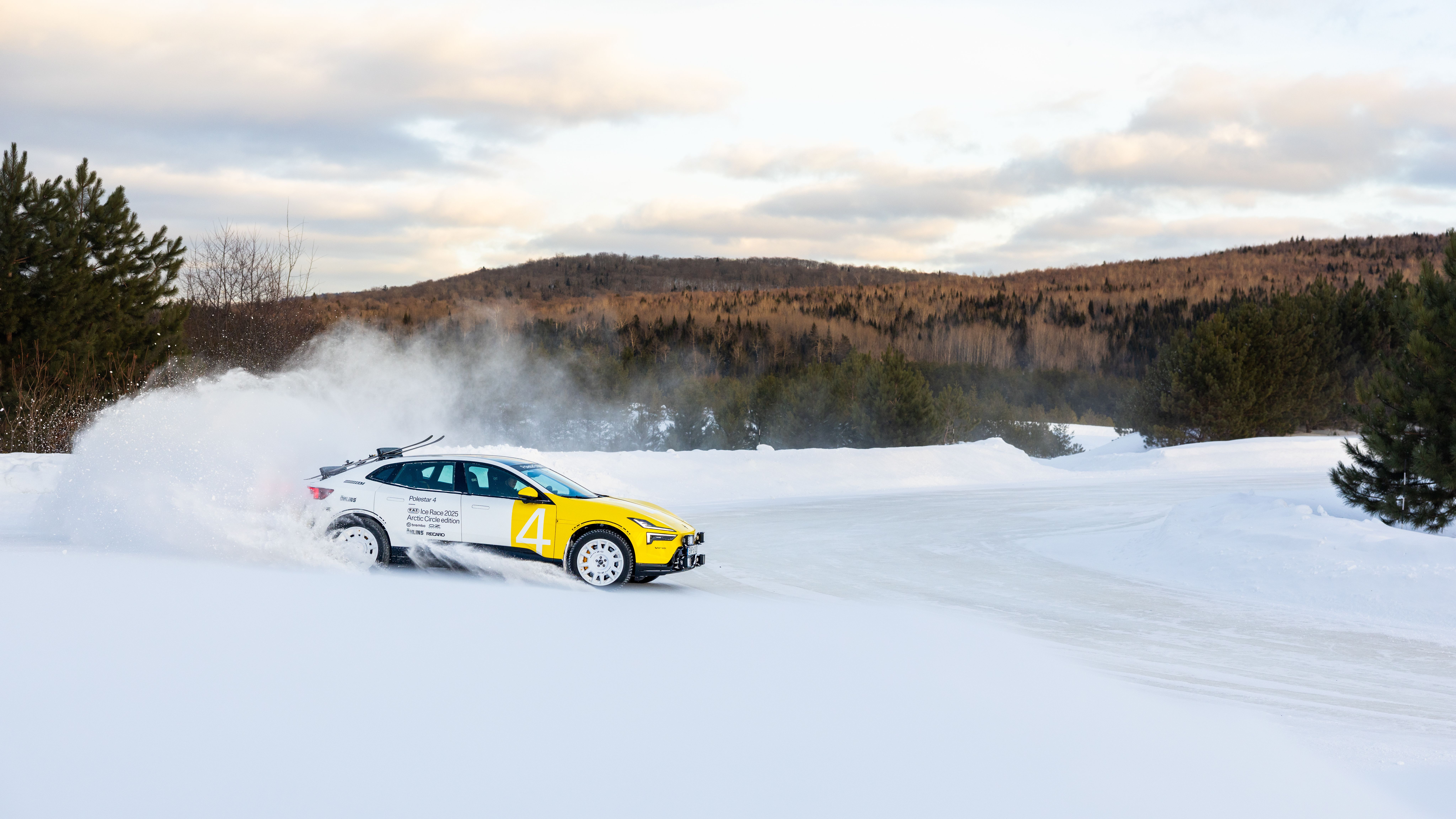 Polestar car on snow track with snow spray, trees and hills in background