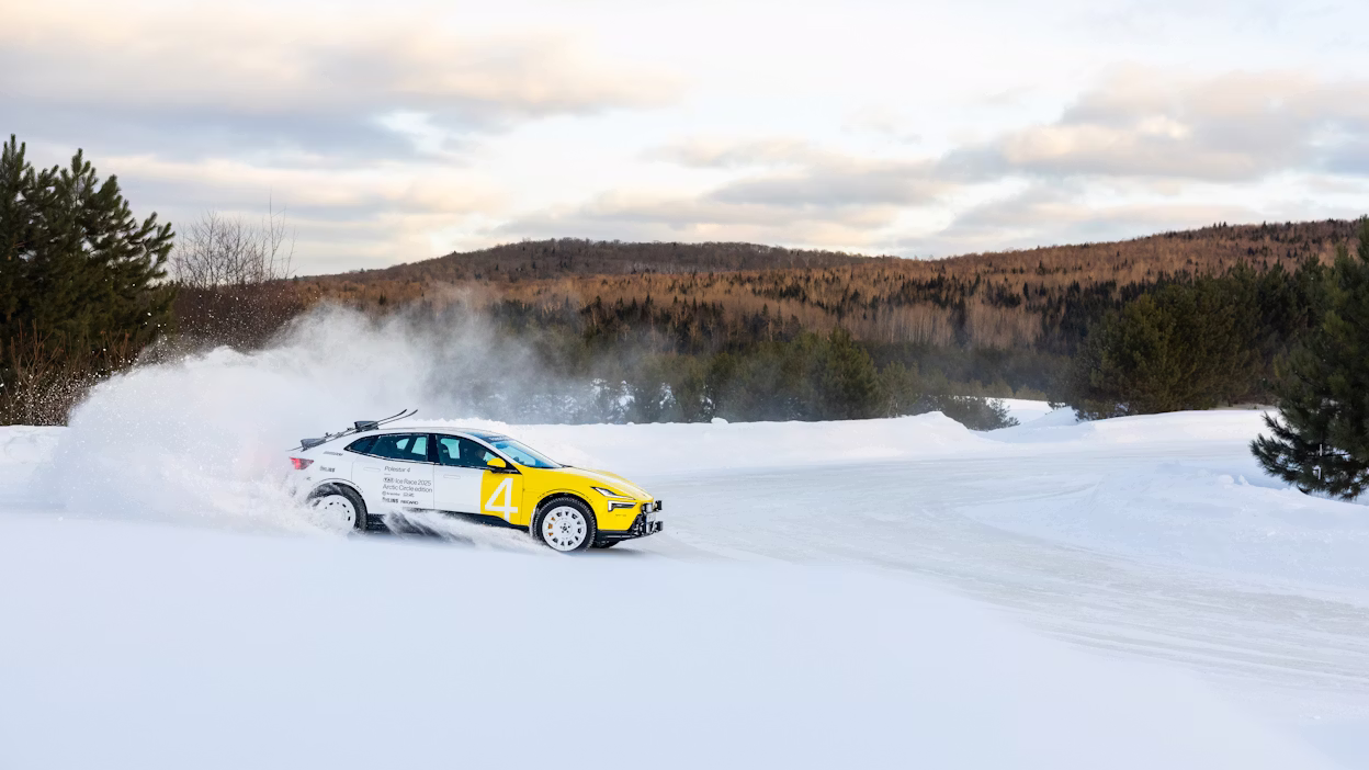 Polestar car on snow track with snow spray, trees and hills in background