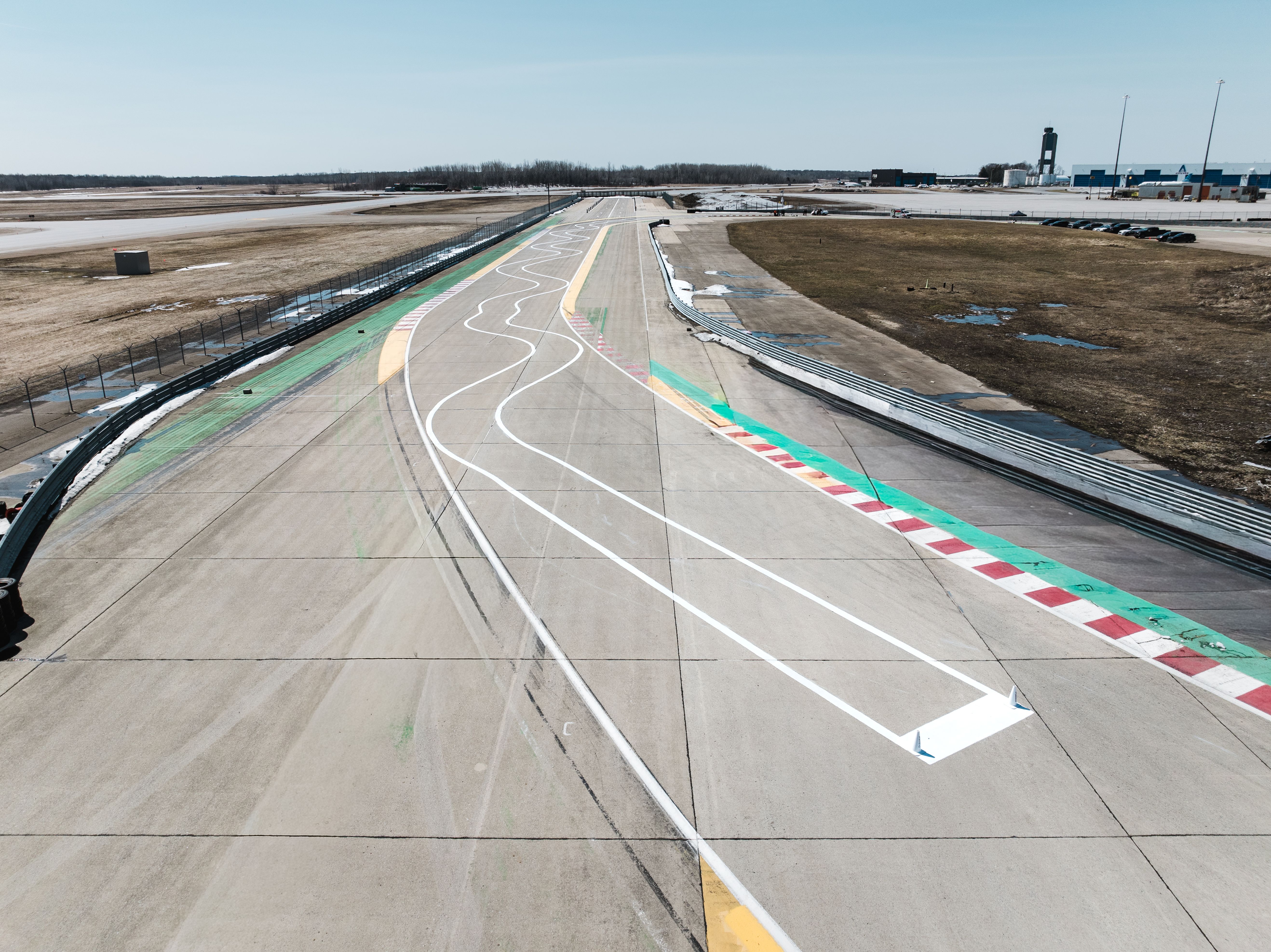 Empty racetrack straightaway with painted lane lines and curbs