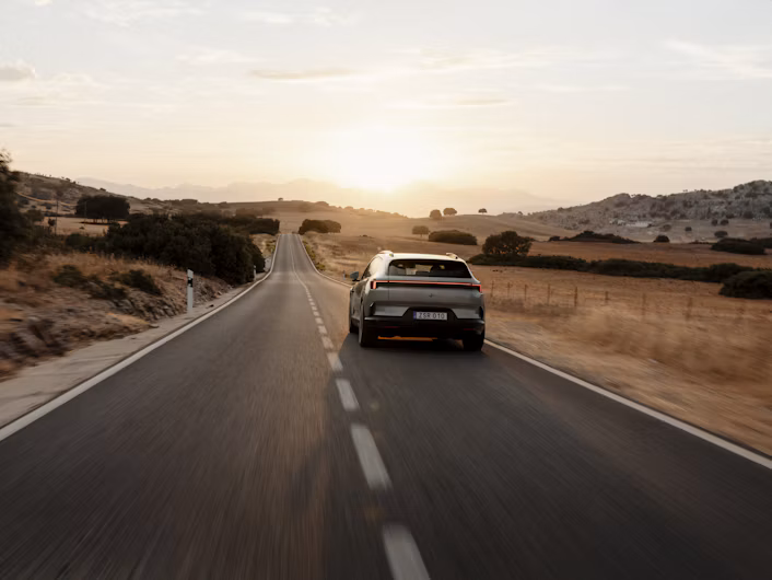 La Polestar 4 SUV percorre una strada di campagna al tramonto.