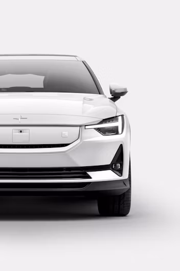 Front view of a white Polestar car with headlights on against a plain background.