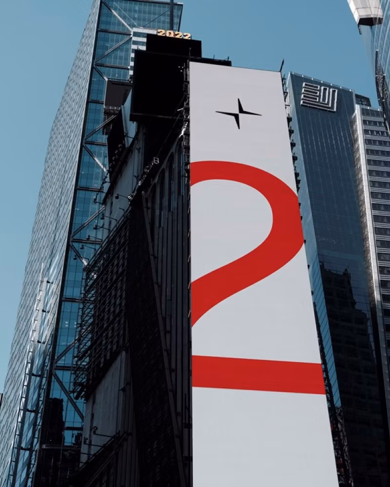Tall building with Polestar logo and large red number 2 on vertical banner, surrounded by other skyscrapers.