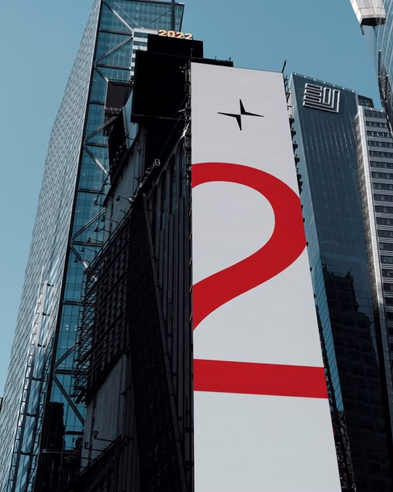 Tall building with Polestar logo and large red number 2 on vertical banner, surrounded by other skyscrapers.