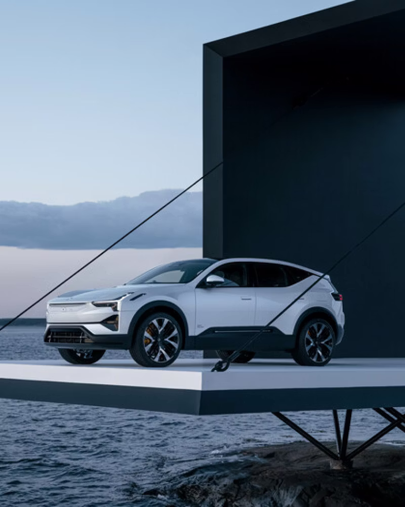 Polestar car on a suspended platform above water with a black geometric structure in the background.