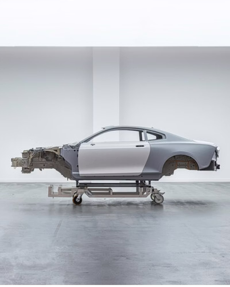 Polestar car frame on a wheeled stand in a white room.