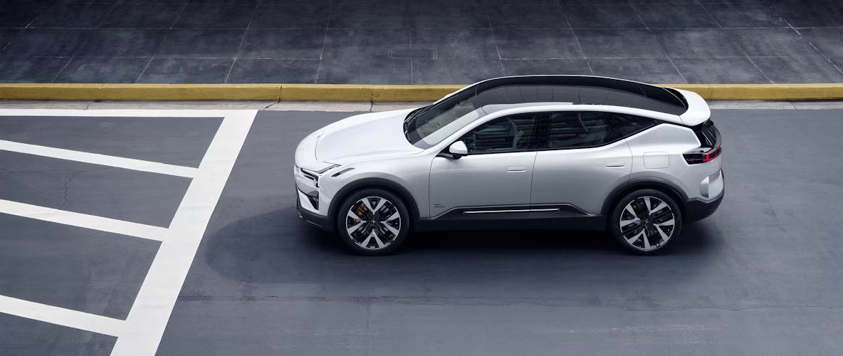 Polestar car parked on a paved surface with road markings and a yellow curb in the background.