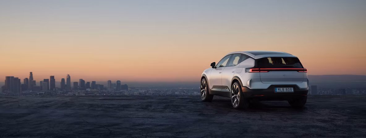 Polestar car parked on a hill overlooking a city skyline at sunset.