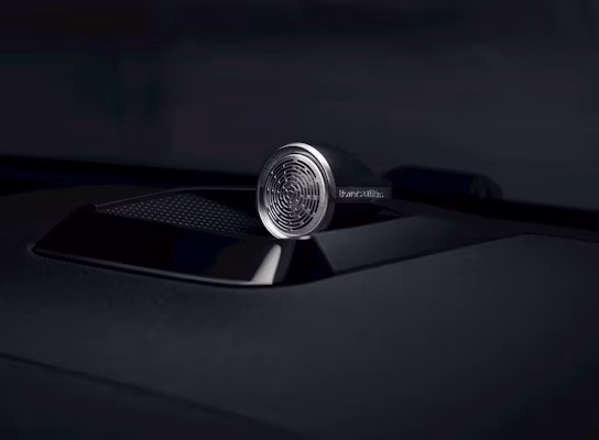 Close-up of a metallic speaker with intricate design on a dark surface, branded with Bowers & Wilkins.