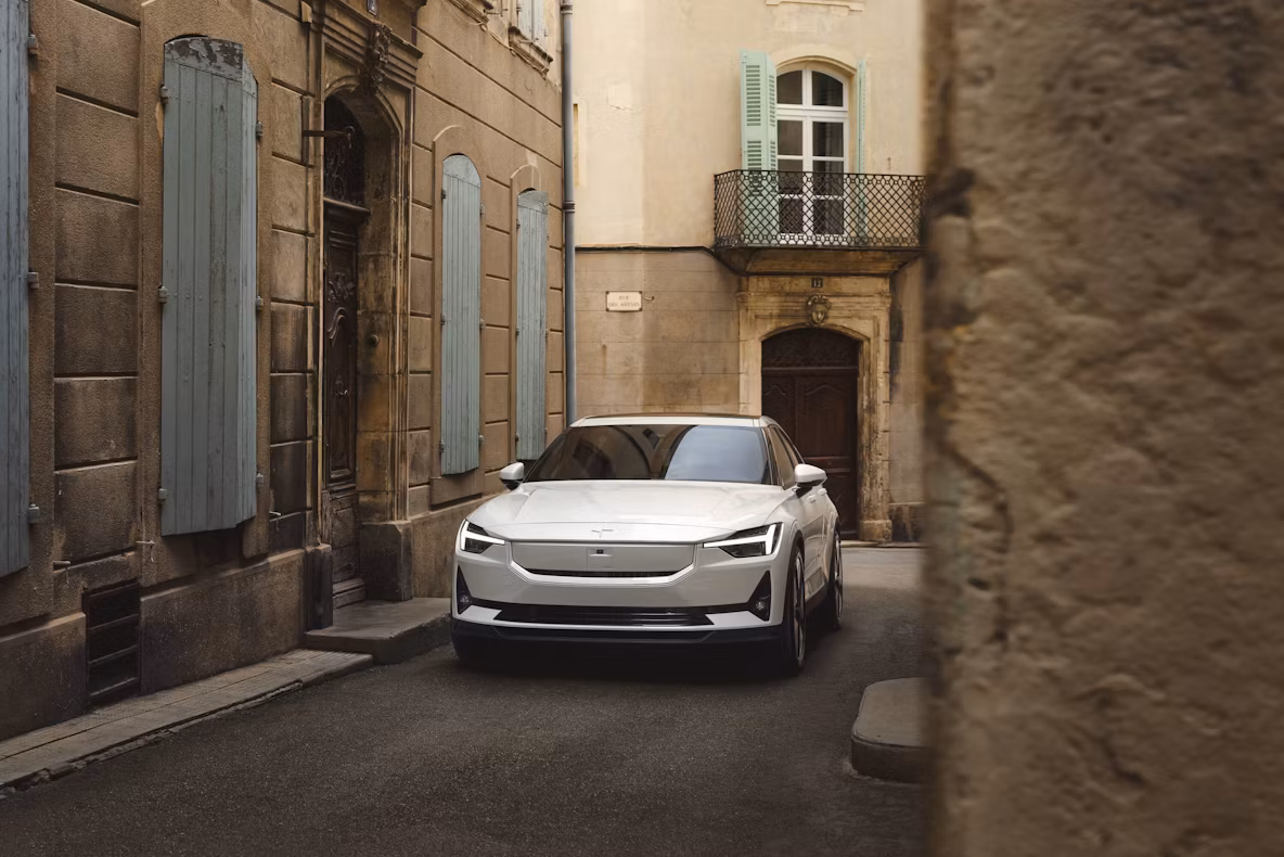 Polestar car parked on narrow street with old buildings and shutters.