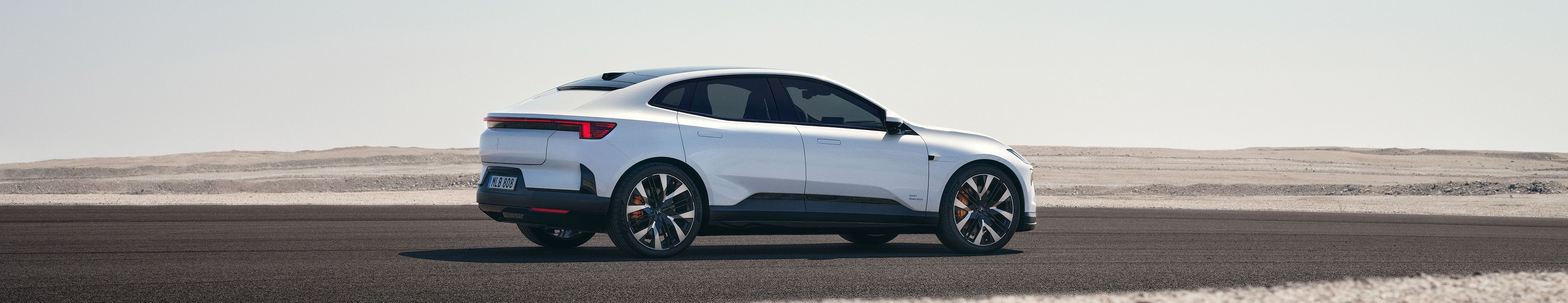 Polestar car parked on asphalt with desert landscape in the background.