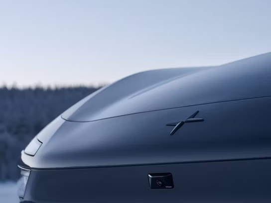 Polestar car rear with logo, snowy forest in background.