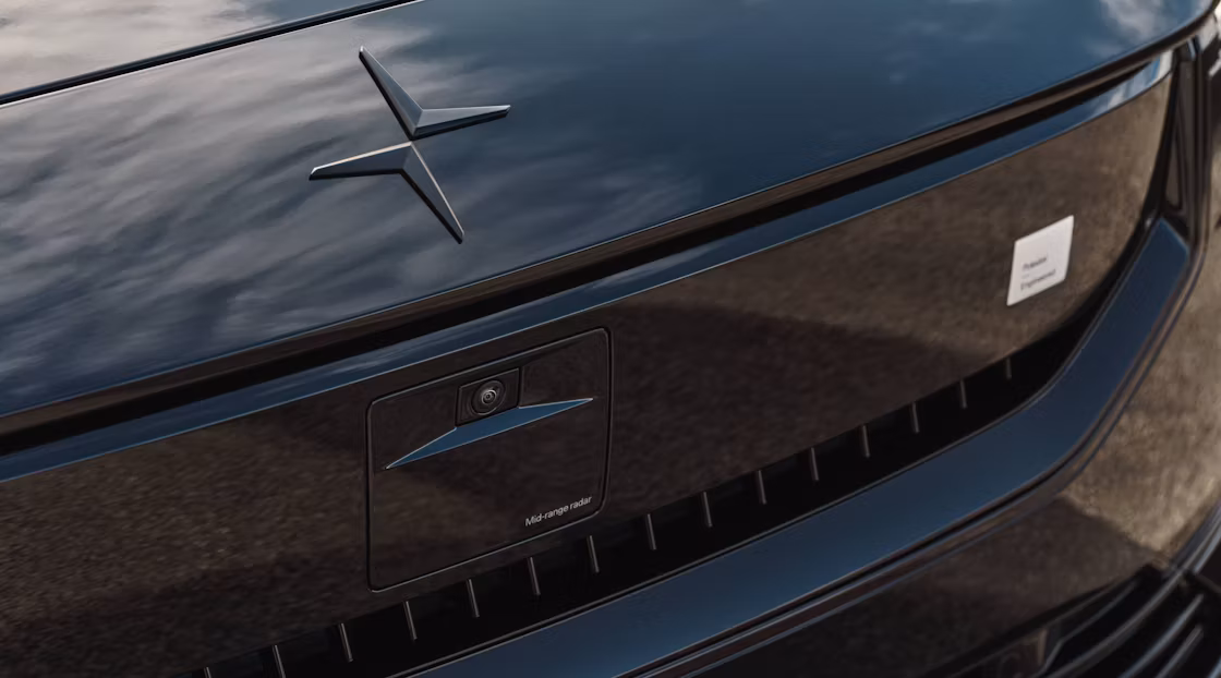 Close-up of Polestar 2’s hood with Polestar logo and smartzone with the sky reflected on surface.